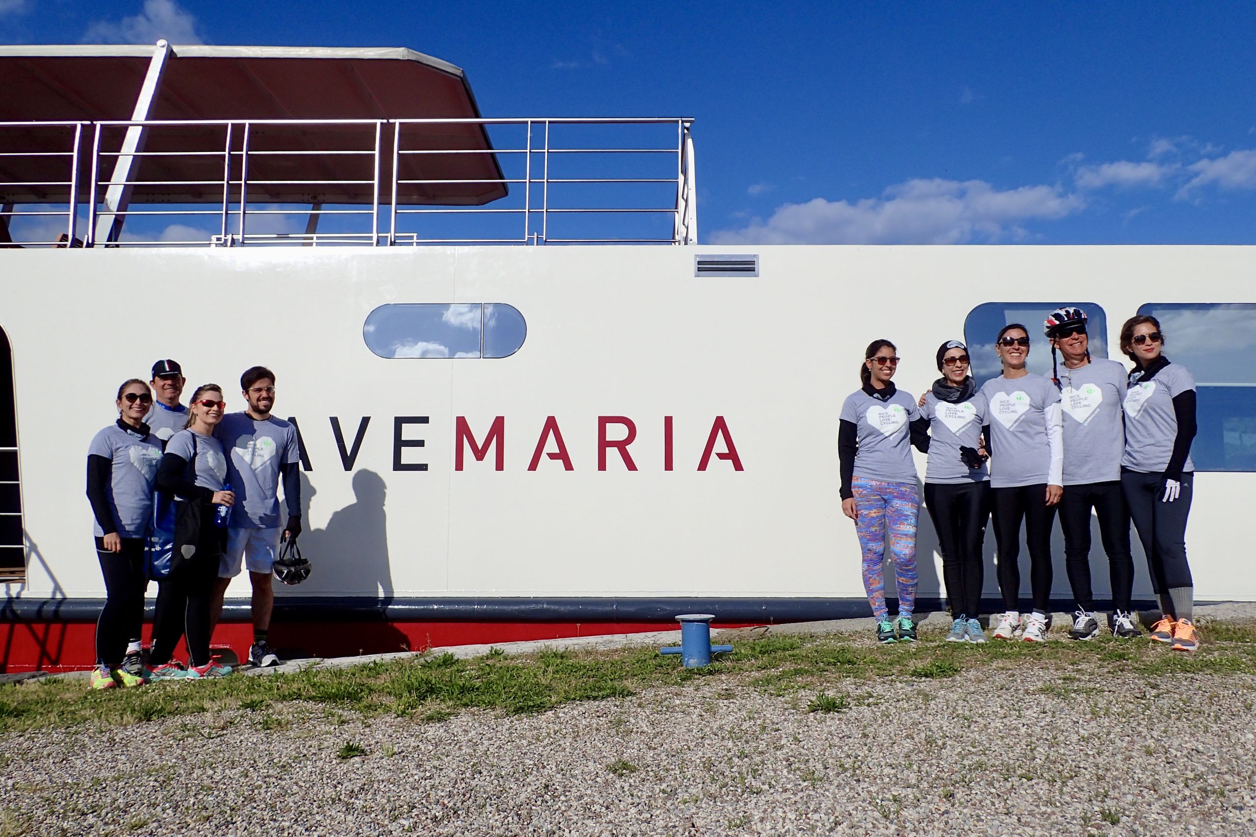 Ciclisti in tenuta sportiva in posa davanti alla barca Ave Maria
